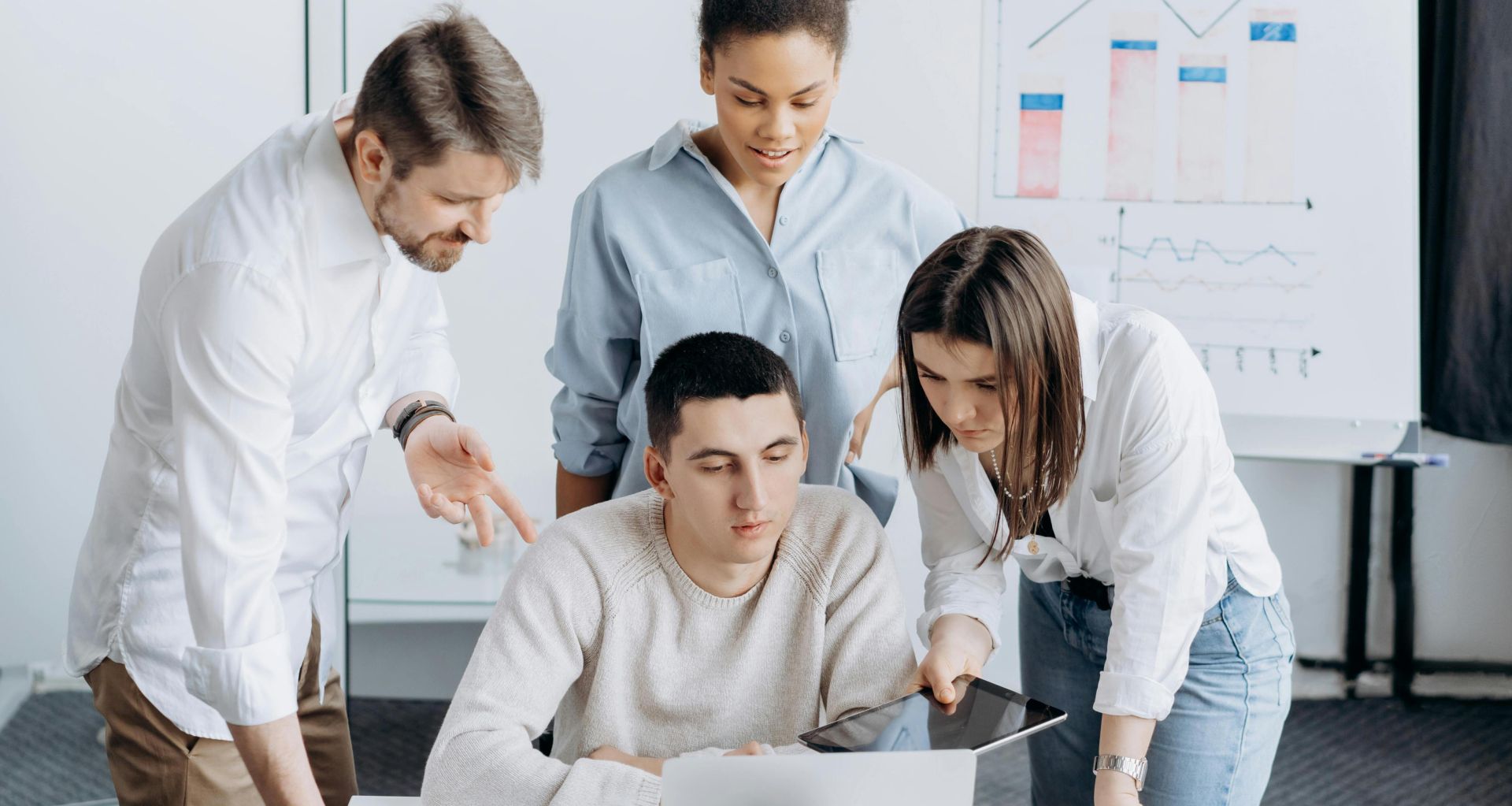 A diverse group of colleagues working together on a business project in an office setting.